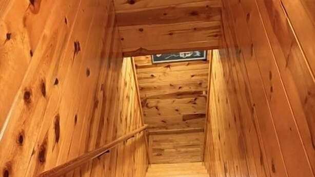 A wooden staircase with a handrail, leading to a landing with a sign.