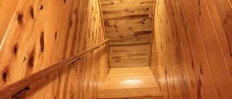 A wooden staircase with a handrail, leading to a landing with a sign.