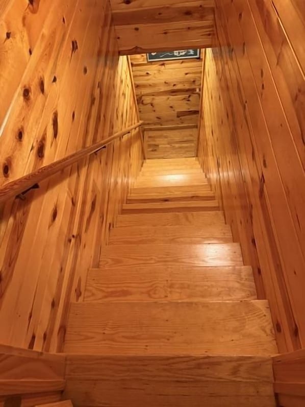 A wooden staircase with a handrail, leading to a landing with a sign.