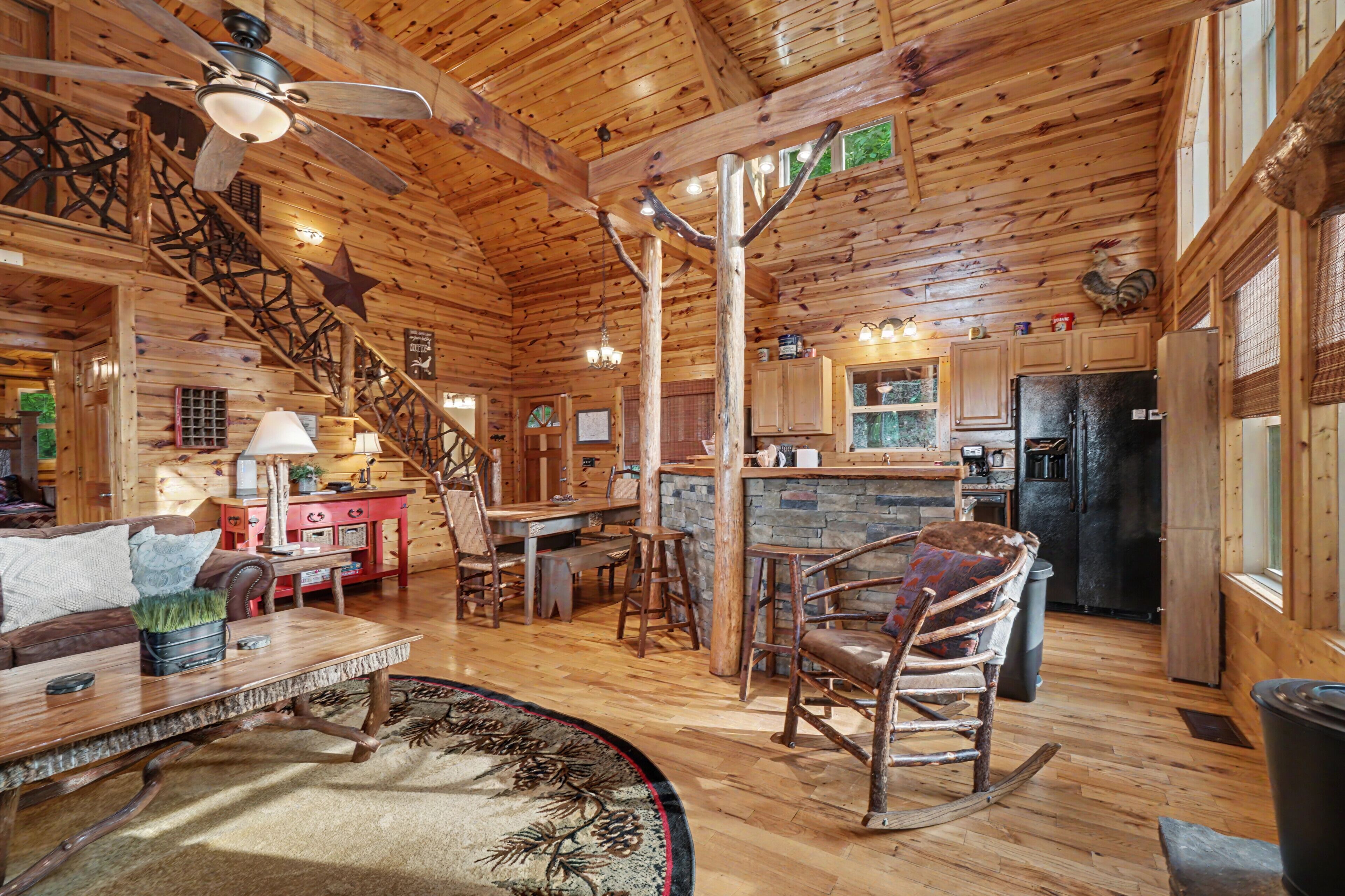 L’intérieur d’un chalet rustique en rondins de bois comprend un coin repas, une cuisine et un escalier.