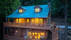 A two-story log cabin with a balcony, a staircase, and a porch area.