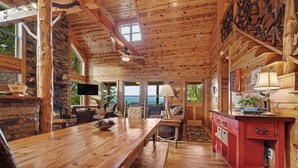 A wooden interior with a stone fireplace, wooden dining table, and a red cabinet.