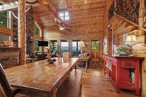 Un intérieur en bois avec une cheminée en pierre, une table à manger en bois et un buffet rouge.