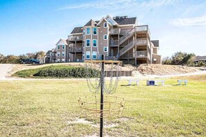 A multi-story residential building with balconies and a grassy area in front. - Barrier Island Station, Duck, NC - 2 Bedroom/Sleeps 8 (Duck)