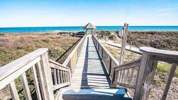 A wooden boardwalk leading to a beach with a small shelter.
