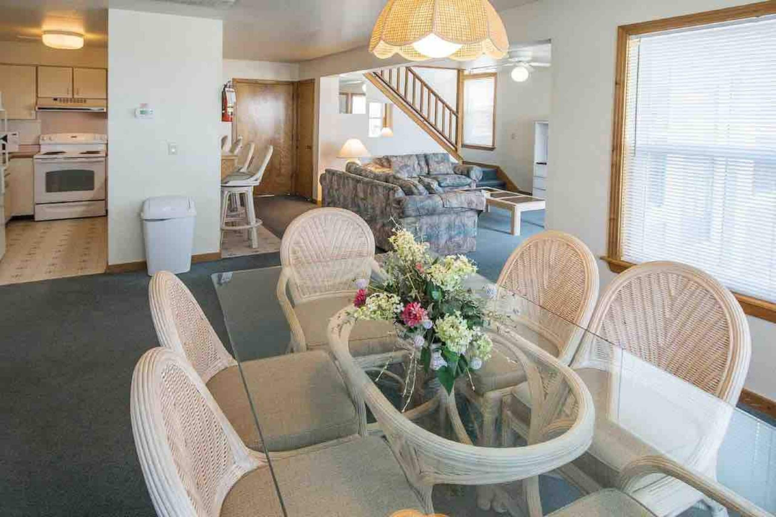 A living room with a dining table, chairs, and a floral centerpiece.