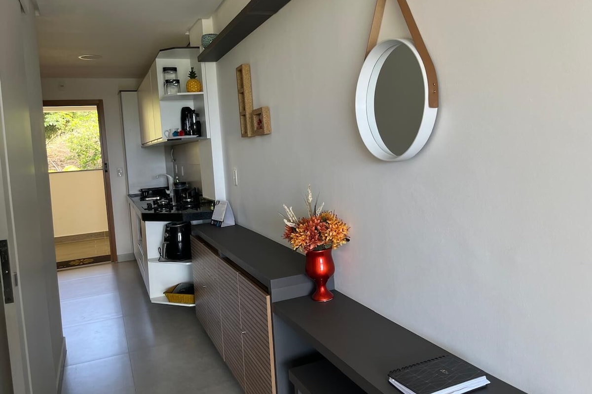 Uma cozinha moderna com máquina de café embutida, um refrigerador pequeno e um armário de madeira.