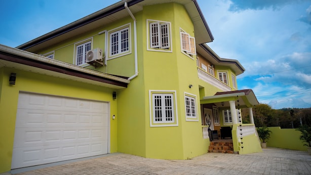 A two-story house with a garage, multiple windows, and a balcony. - Experience the Caribbean sophistication at this Ultra-modern, 6 Bedroom En-suite (Plymouth)