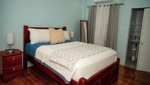 A bedroom with a bed, bedside table, lamp, and an air conditioning unit. - Experience the Caribbean sophistication at this Ultra-modern, 6 Bedroom En-suite (Plymouth)