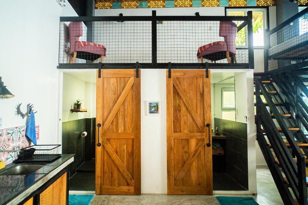 Un hall de hotel con una puerta de madera, una escalera y una silla roja.