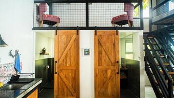 Un hall de hotel con una puerta de madera, una escalera y una silla roja.