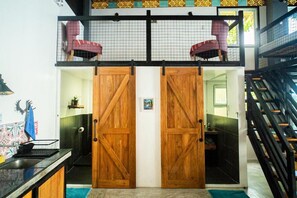 Un hall de hotel con una puerta de madera, una escalera y una silla roja.