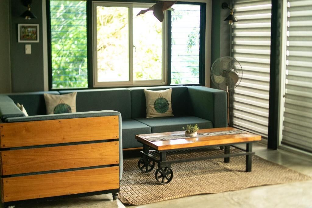 Una sala de estar con un sofá, un aparador de madera, una mesa de centro y una ventana con persianas.