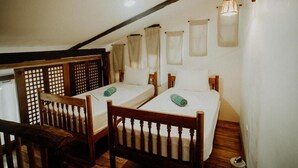 A room with two single beds, wooden furniture, and a sloped ceiling.