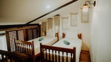 Une chambre avec deux lits simples, des meubles en bois et un plafond en pente.