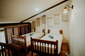 Una habitación con dos camas individuales, muebles de madera y techo inclinado.