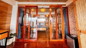 A room with a wooden ceiling, a bed, a desk, and a refrigerator.