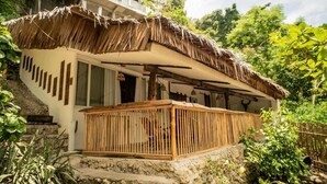 A thatched-roof structure with a wooden balcony, surrounded by greenery. - Fantasy Lodge (Samboan)