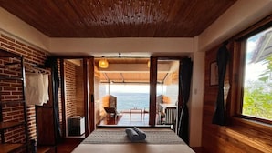 A room with a bed, a view of the sea, and a balcony with a table and chairs. - Fantasy Lodge (Samboan)