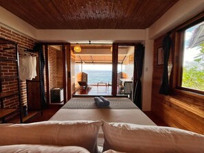 Una habitación con cama, vistas al mar y un balcón con mesa y sillas.