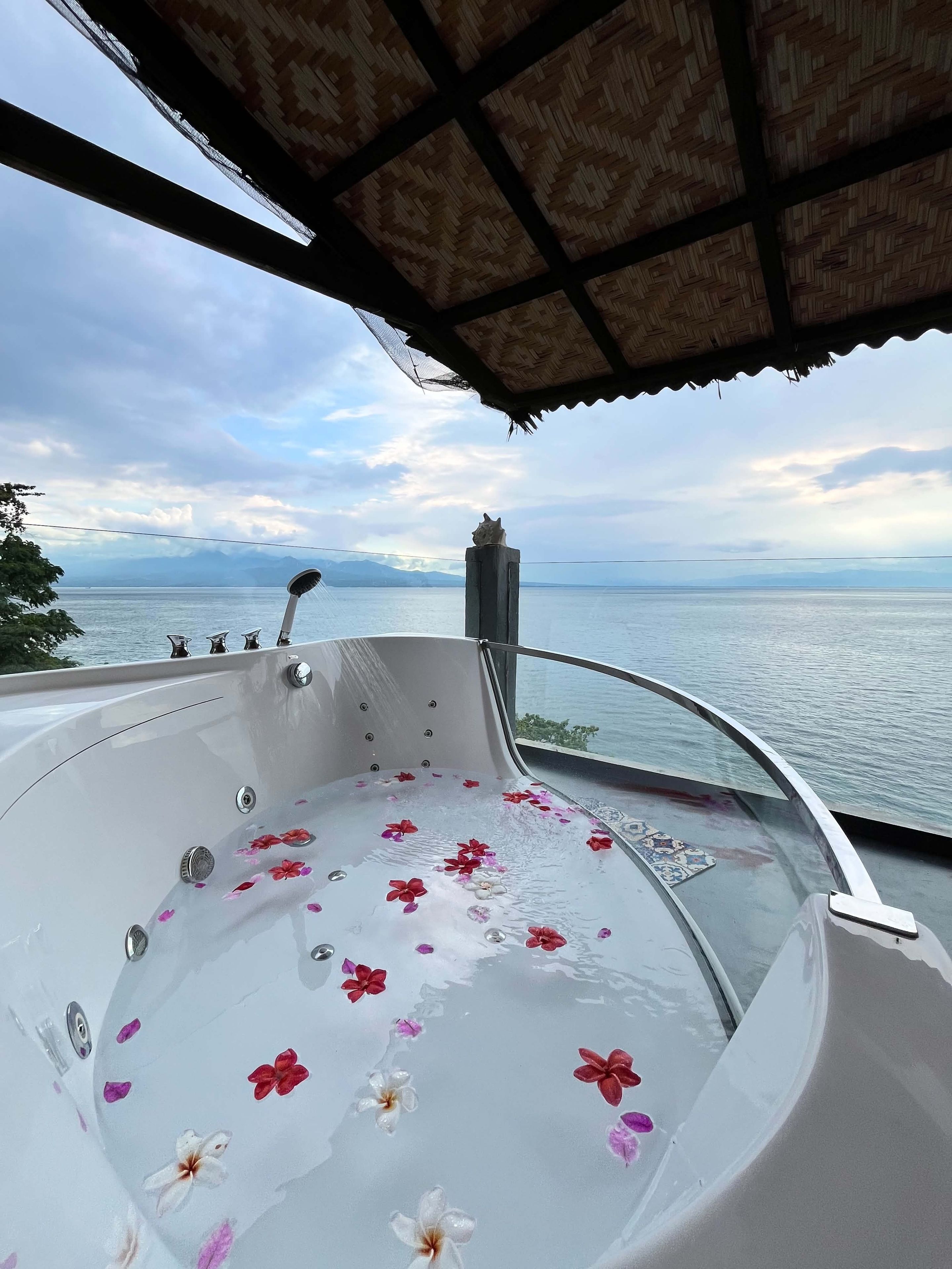 A hot tub with floral decorations and a view of the sea.
