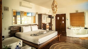 A hotel room with a large bed, a bathtub, a bathroom with a sink, and a chandelier. - Fantasy Lodge (Samboan)
