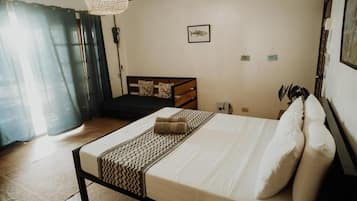 A bedroom with a bed, a bedside table, a lamp, and a window with curtains.