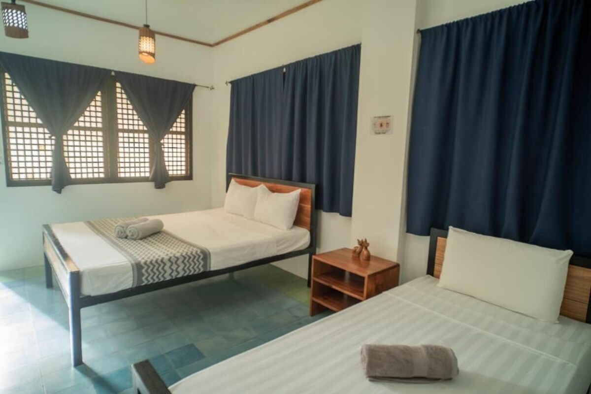 Una habitación con una cama, una mesita de noche y un ventanal con cortinas.