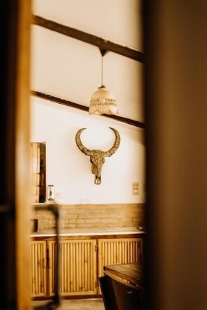 Una habitación con techo de madera, una lámpara colgante y una cabeza de toro montada en la pared.