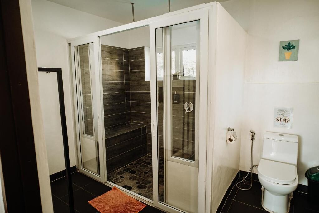 Une salle de bain avec une douche à parois de verre, des toilettes et un petit tapis sur le sol.