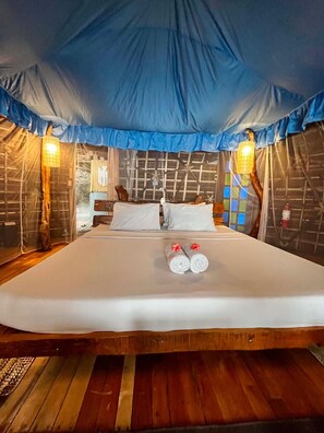 A bed with white linens, two pillows, and two rolled towels with a red flower. - Fantasy Lodge (Samboan)