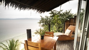 A wooden deck with a table and chairs, overlooking a body of water. - Fantasy Lodge (Samboan)