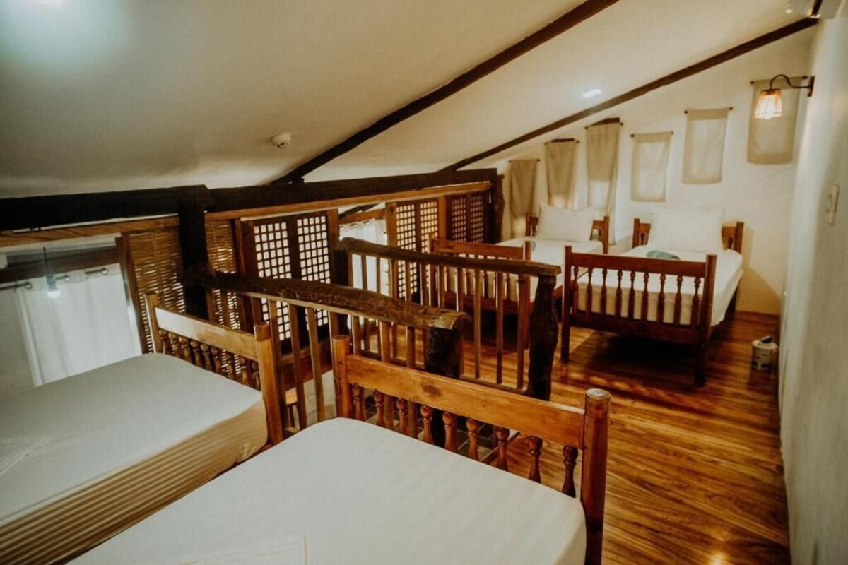 Una habitación con una cama de madera, una silla de madera y una mesita pequeña.