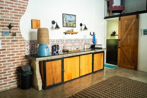 Una cocina con pared de ladrillo, un armario de madera, una cesta tejida y un cuadro en la pared.