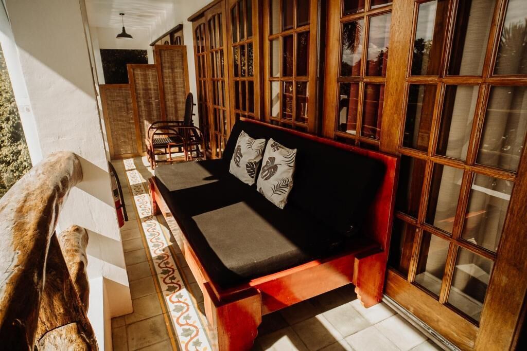 Una habitación con un banco de madera, un asiento acolchado y un ventanal de varios cristales.
