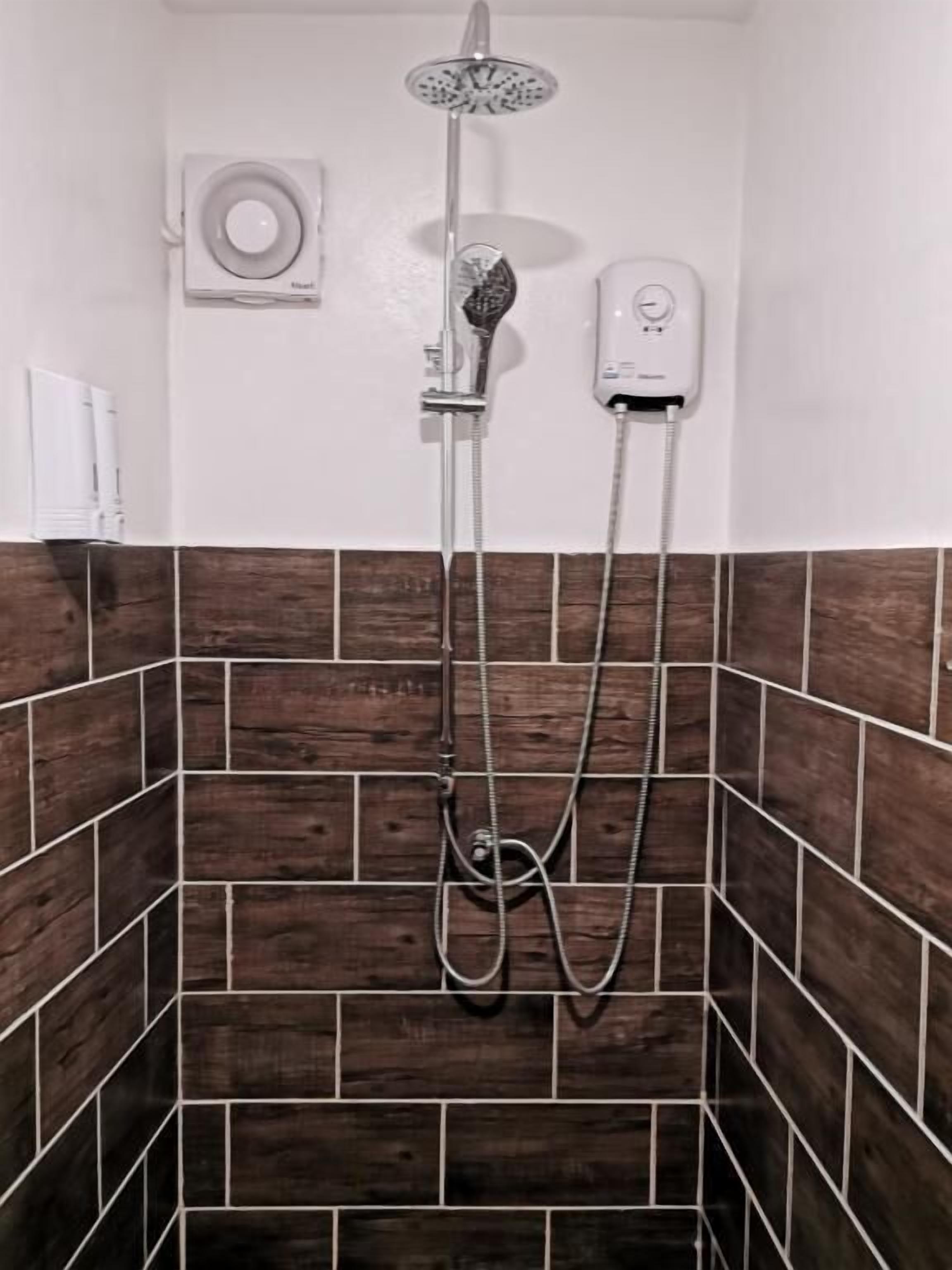 A shower area with a handheld showerhead and a wall-mounted faucet.