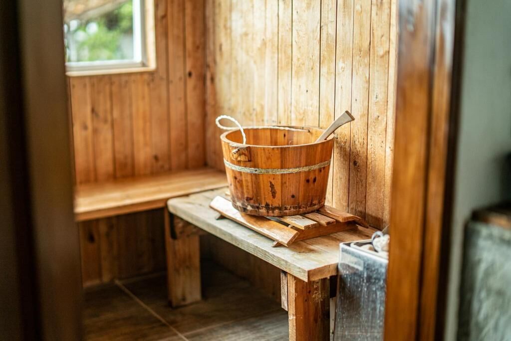 Un banco de sauna de madera con un balde de madera encima.
