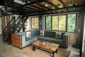 A living room with a sectional sofa, a coffee table, and a staircase. - Fantasy Lodge (Samboan)