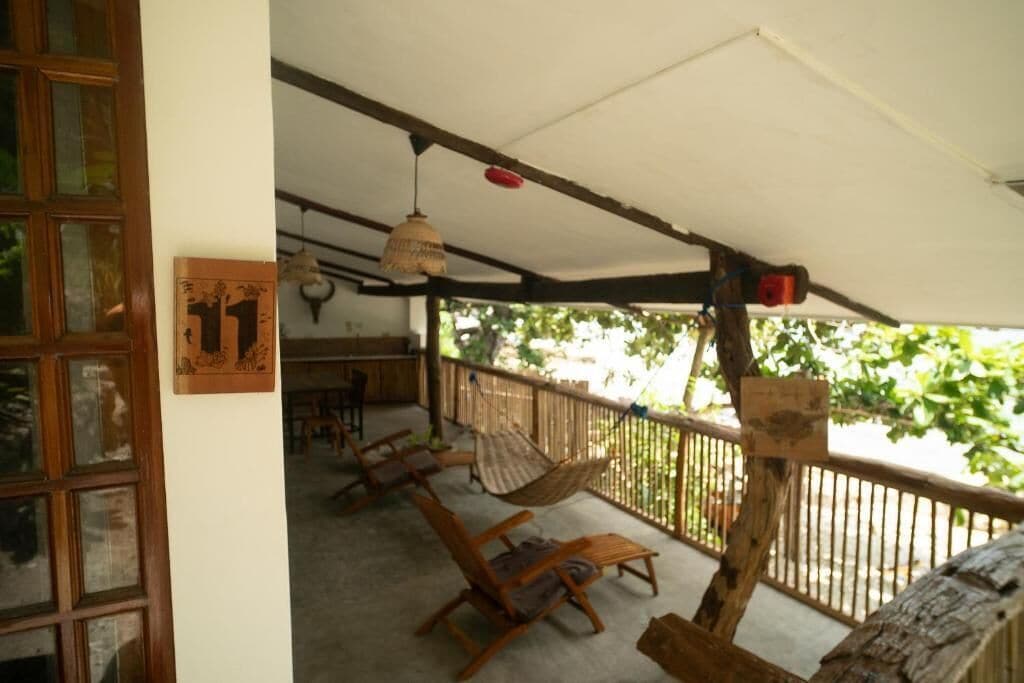 Area esterna coperta con mobili in legno e una lampada a sospensione.