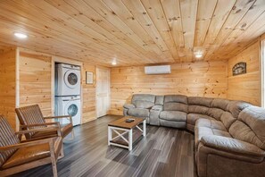 Een gezellig houten interieur met een slaapbank, een bijzettafeltje en een wasmachine.