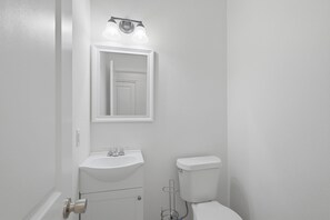 A bathroom with a white sink, a toilet, and a mirror above the sink.