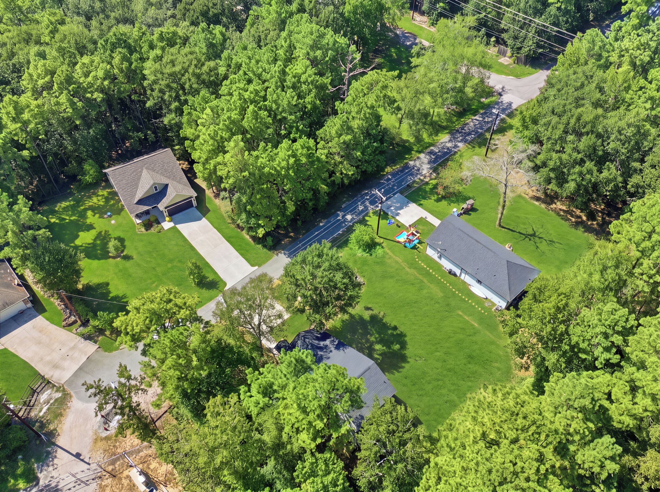 An aerial view of a residential area with multiple houses, a swimming pool, and a well-maintained lawn.
