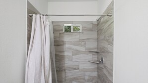 Una ducha con cortina, ventana y pared con azulejos.