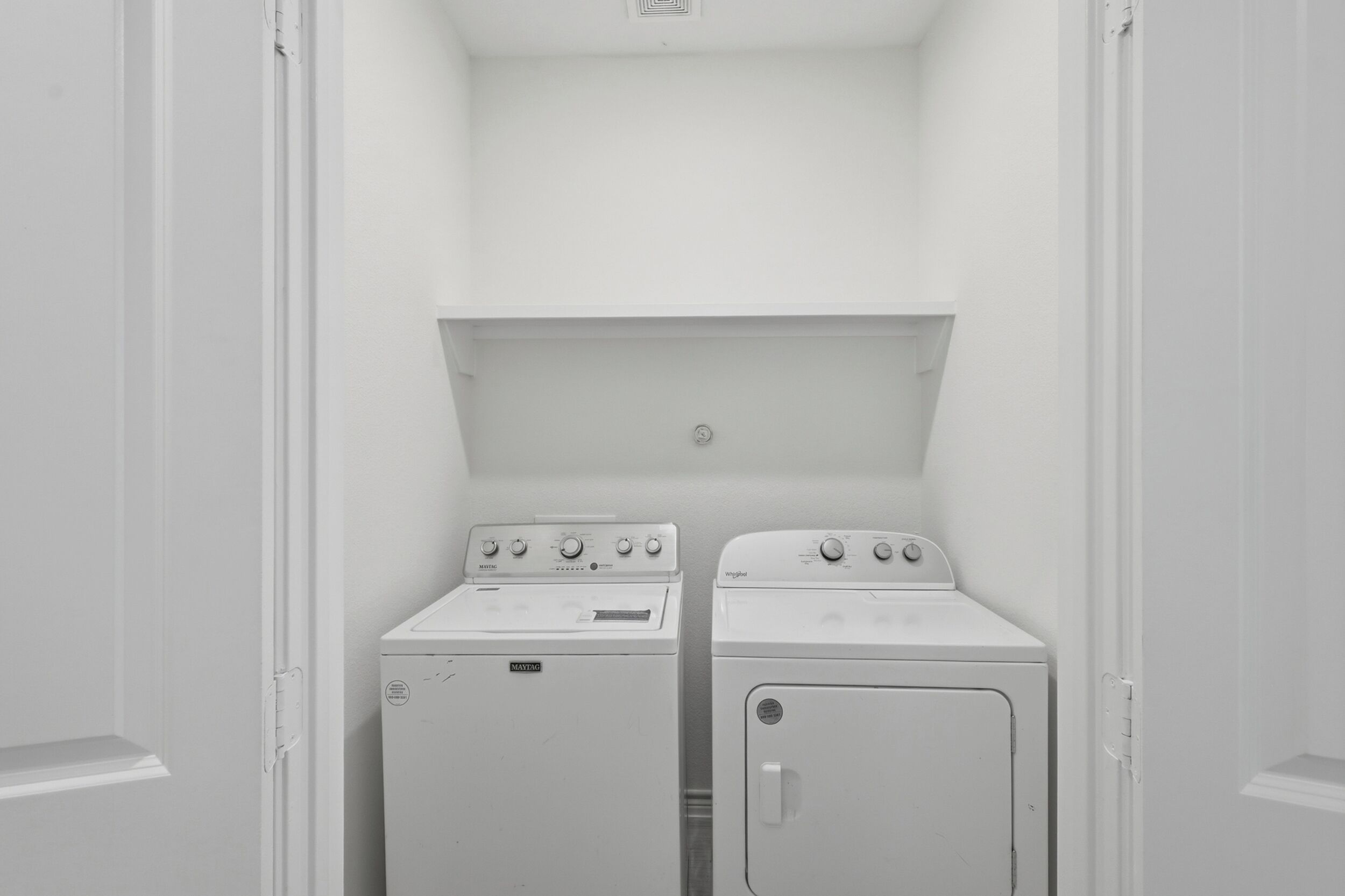 Une buanderie équipée de deux machines à laver blanches et d’un sèche-linge.