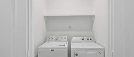 A laundry room with two white washing machines and a dryer.