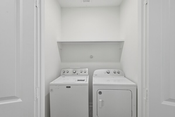 A laundry room with two white washing machines and a dryer.