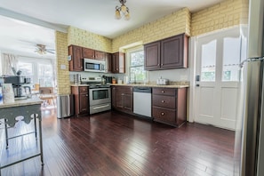 A kitchen with dark wooden cabinets, a stainless steel refrigerator, and a granite countertop. - Stone Pool House - Sleeps 8 (Columbus)