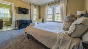 A bedroom with a large bed, a flat-screen TV mounted on the wall, and a ceiling fan. - Stone Pool House - Sleeps 8 (Columbus)