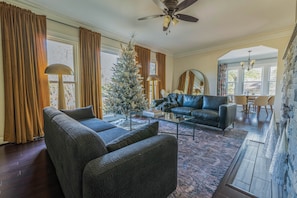 A living room with a fireplace, a Christmas tree, and a dining area. - Stone Pool House - Sleeps 8 (Columbus)