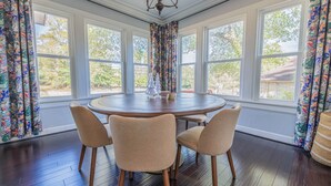 A dining area with a round table and four chairs, large windows, and a chandelier. - Stone Pool House - Sleeps 8 (Columbus)